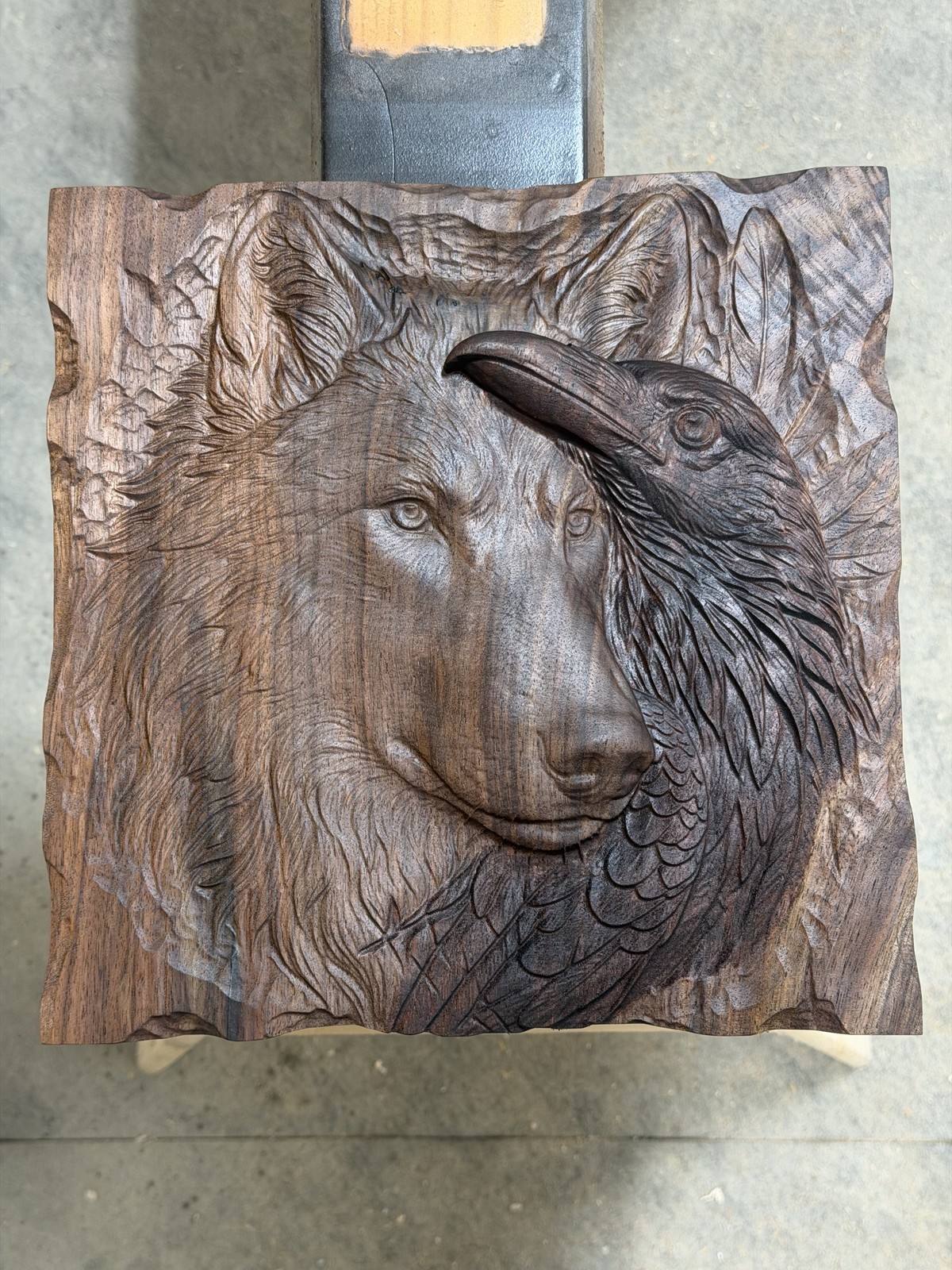 The wolf and raven carving after its first coat of boiled linseed oil, the walnut turned rich brown and the raven nearly black
