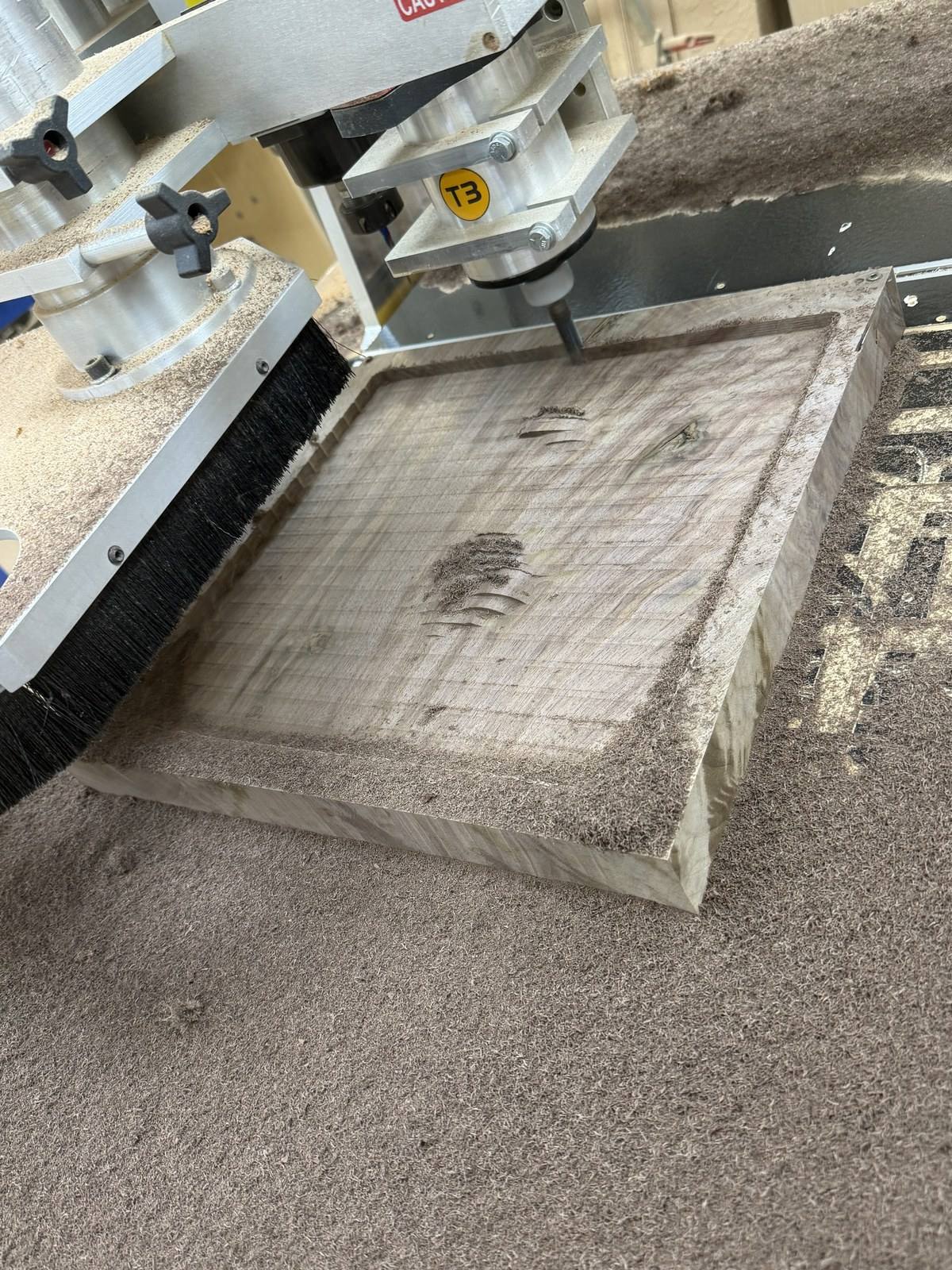 Jeff Miller's CNC router roughing a 15 inch walnut board with a corn cob roughing end mill, sawdust across the board