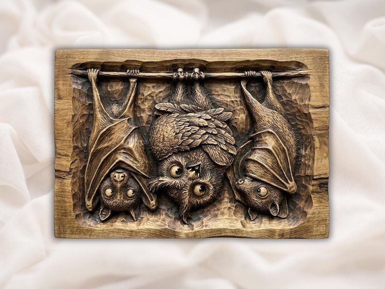 Bas-relief wood carving of two bats hanging upside down beside a roosting owl in a chiseled frame