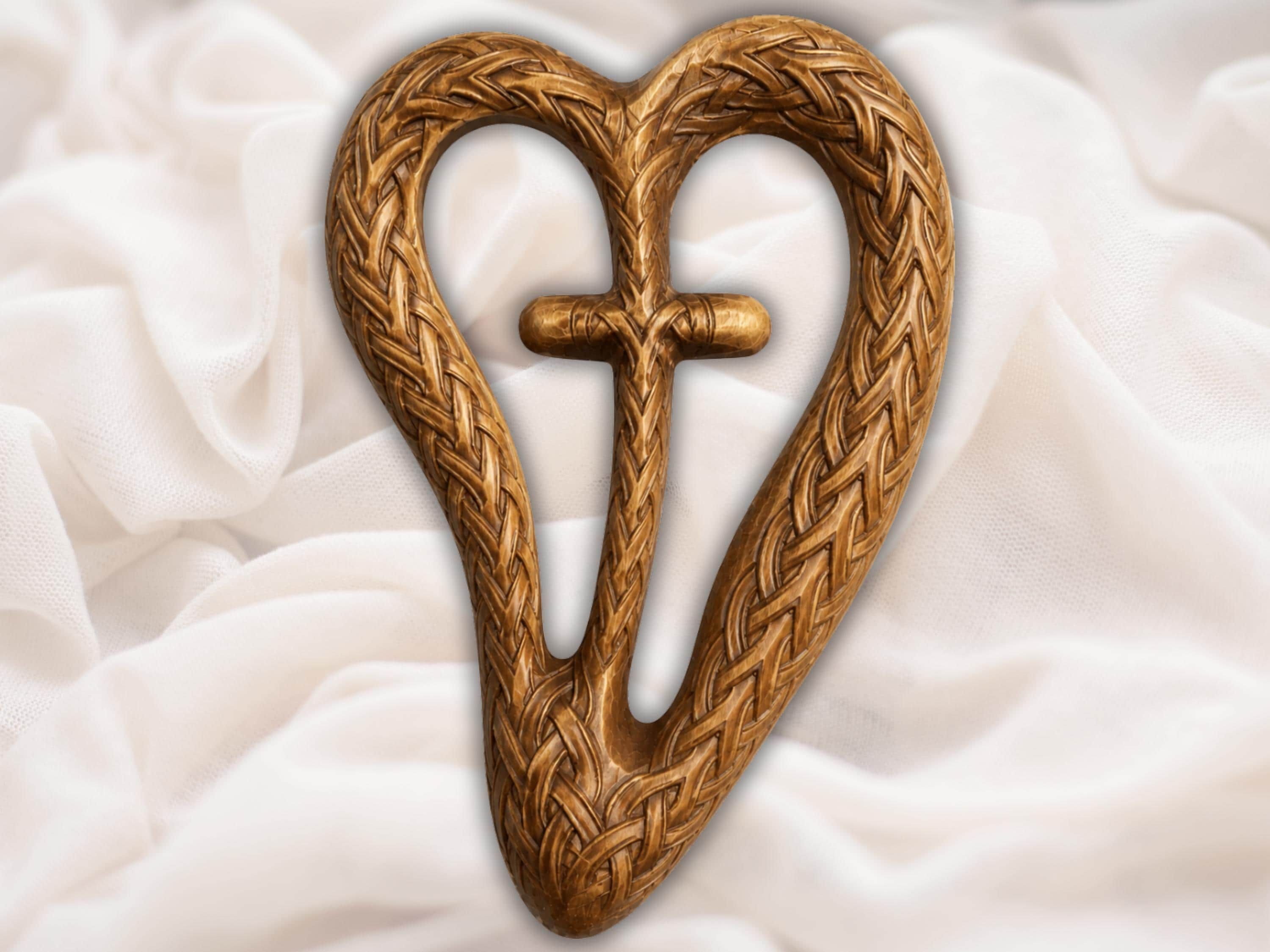 Bas-relief carving of a heart made from braided Celtic knotwork with a raised cross at its center in wood