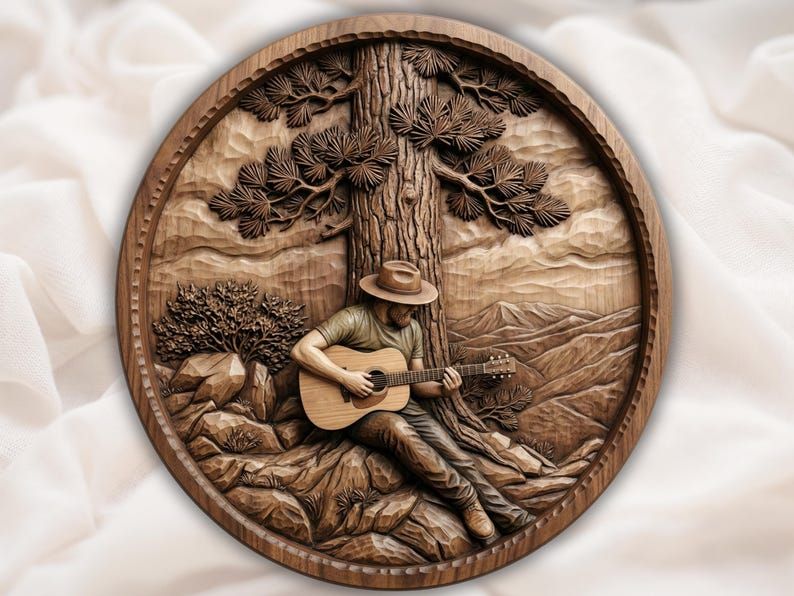 Round wood relief carving of a cowboy in a hat playing guitar under a pine tree with mountains behind.