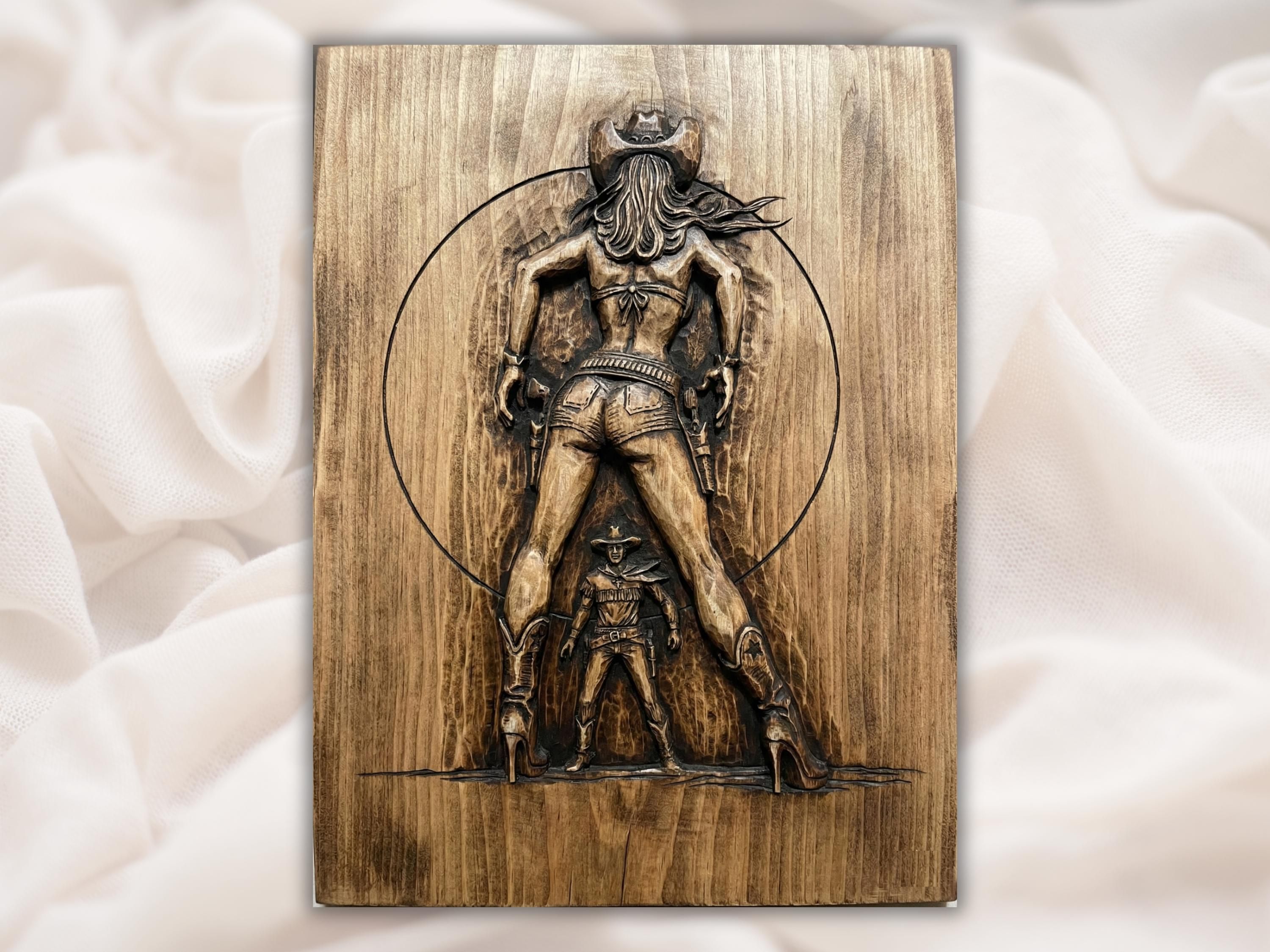 Carved wood bas-relief of a cowgirl in hat and pistols standing over a small standing gunslinger.