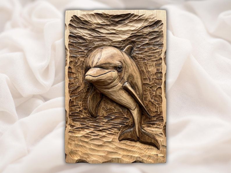 Carved wood bas-relief of a bottlenose dolphin swimming through textured rippling water on a rectangular panel
