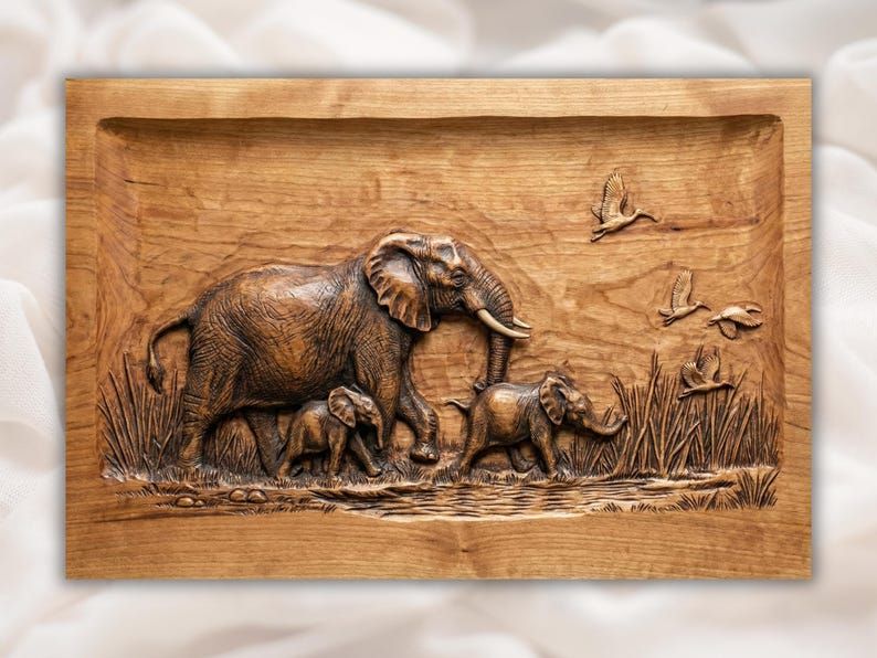 Carved wood bas-relief of a mother elephant with two baby elephants by a river with birds in flight
