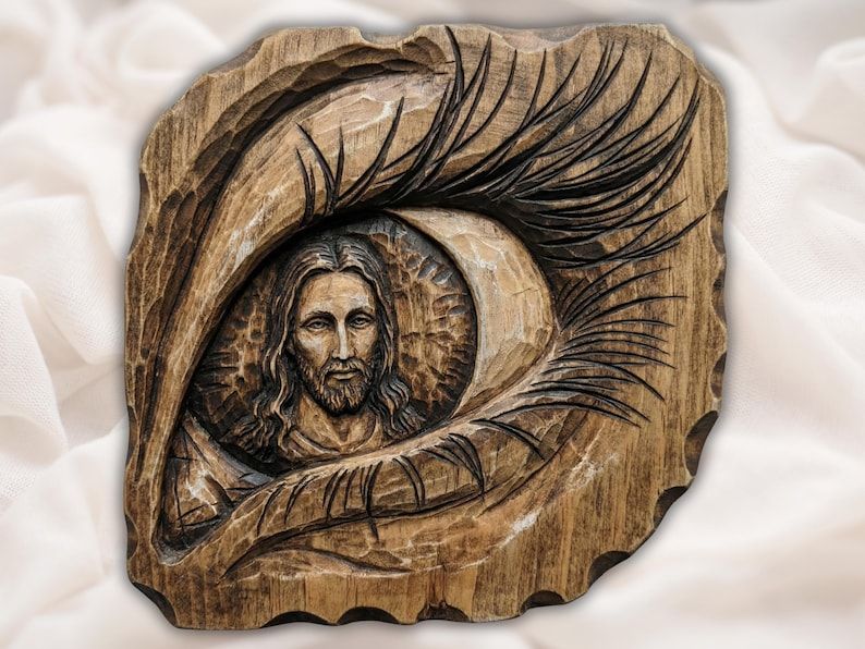 Bas-relief wood carving of a human eye with the face of Jesus reflected inside the iris and long carved lashes