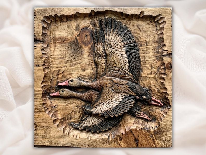 Carved wood bas-relief of two ducks flying together with spread wings inside a rustic framed panel.