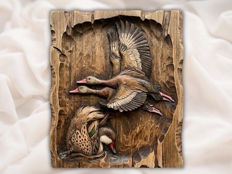 Bas-relief wood carving of two whistling ducks in flight and one swimming on a rough-edged plaque