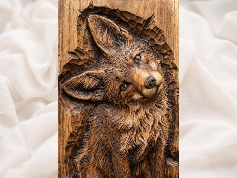 Carved wood bas-relief of a young fox tilting its head, detailed fur and bright eyes on a panel