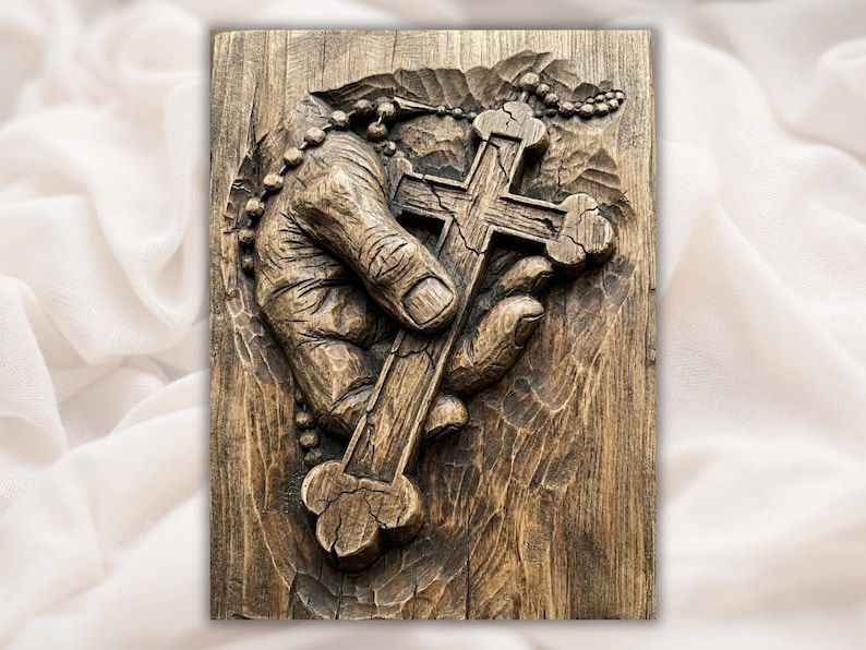 Wood-carved relief of a weathered hand holding an Orthodox three-bar cross with rosary beads draped across it