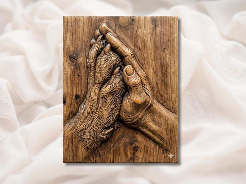 Bas-relief wood carving of a human hand gently holding a dog's paw, set on a warm wood panel.