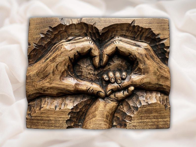 Carved wood bas-relief of two adult hands forming a heart around a small child's hand