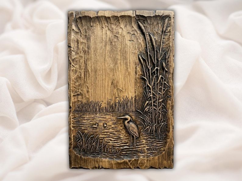 Bas-relief wood carving of a great blue heron standing in a marsh among cattail reeds with ducks on rippling water.
