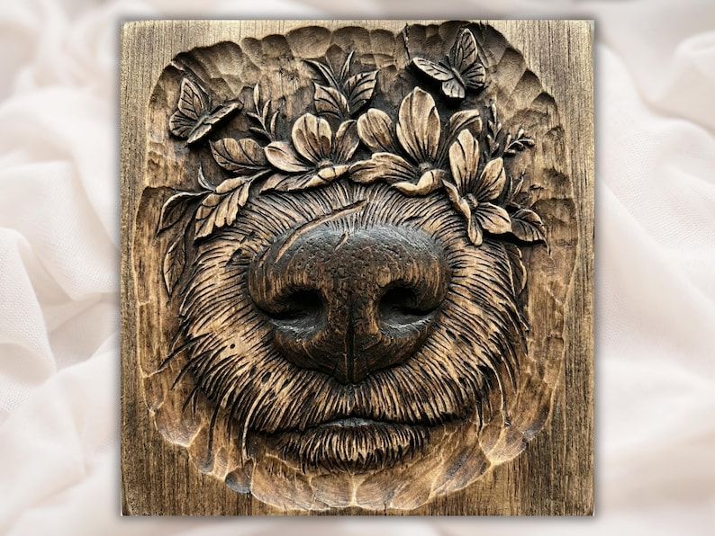 Carved wood relief of a bear muzzle and nose framed by fur, with magnolia flowers and butterflies above