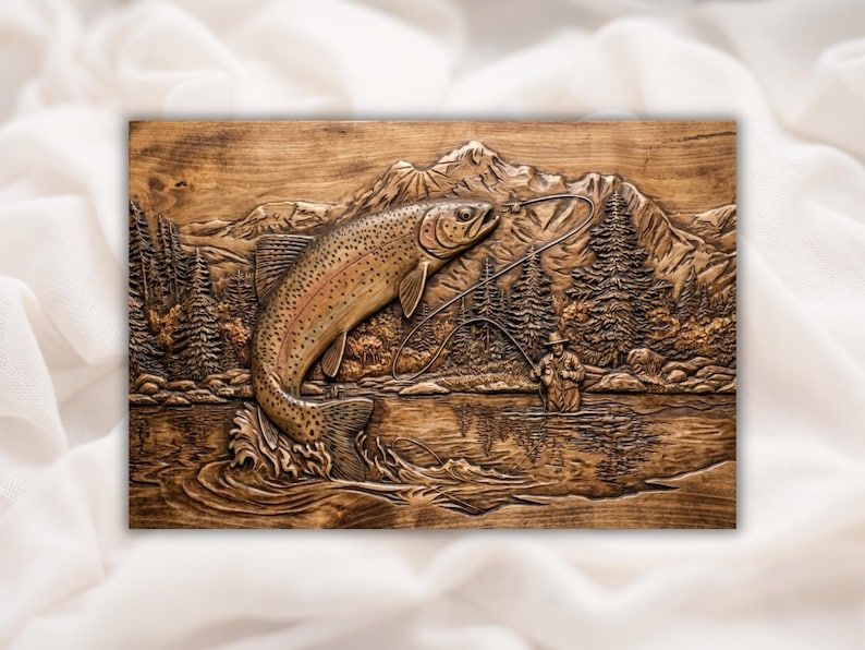 Wood-carved relief of a rainbow trout leaping from a river with mountains, pines, and a fly fisherman