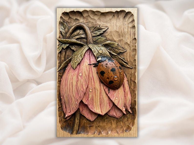 Carved wood bas-relief of a ladybug resting on a drooping pink blossom with dew drops and leaves