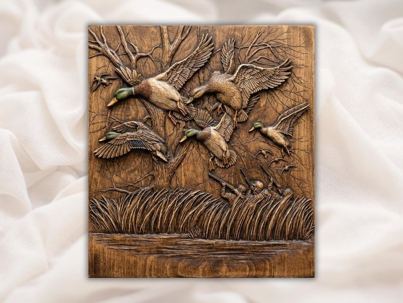 Carved wood relief of mallard ducks flying up from marsh reeds with bare tree branches and water below