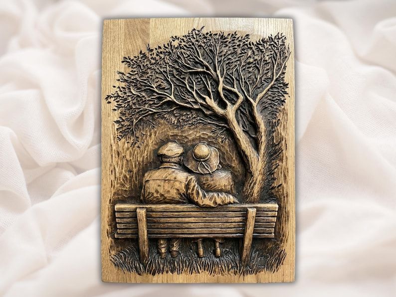 Bas-relief wood carving of an elderly couple sitting on a bench under a large tree
