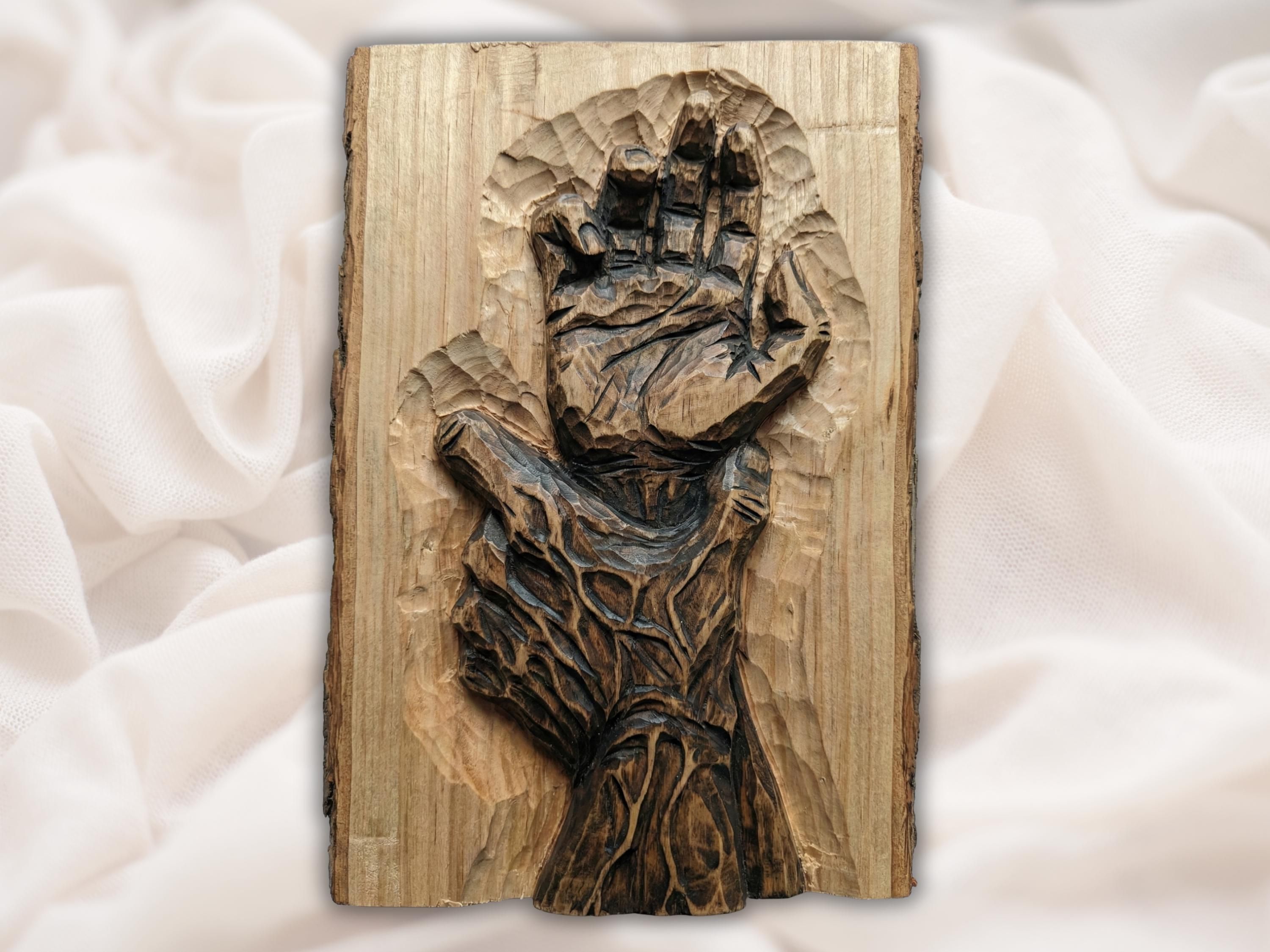 Carved wooden relief of an open hand reaching upward, rising from twisted root and grain texture