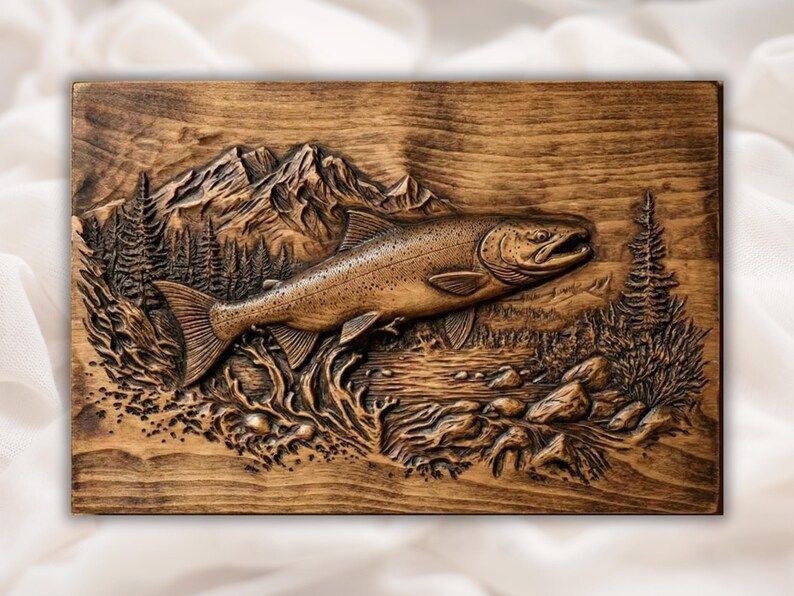 Carved wood bas-relief of a leaping trout over a rocky river with pine trees and mountains