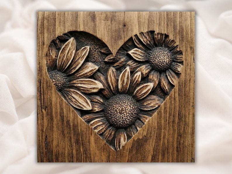 Bas-relief wood carving of three sunflowers arranged inside a heart shape on a stained wood panel