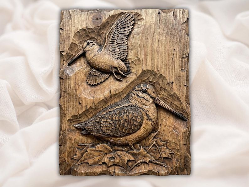 Bas-relief wood carving of two woodcock birds, one flying with wings spread and one resting on leaves.